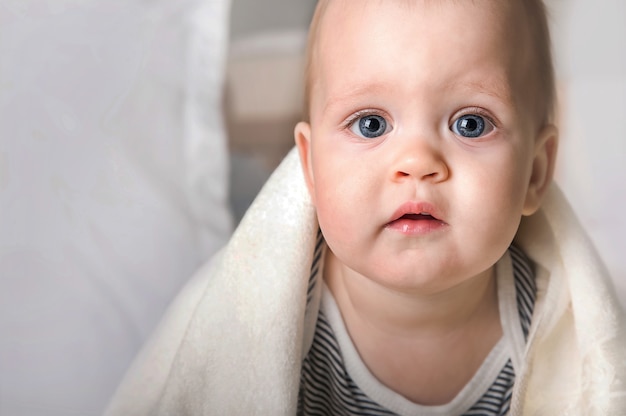 Close up portrait 9 month old baby with white towel Teething bathing healthy sleep toddler