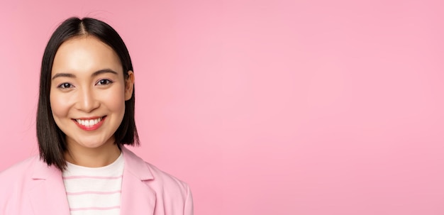 Close up portrait of asian corporate woman looking professional smiling at camera wearing suit stand