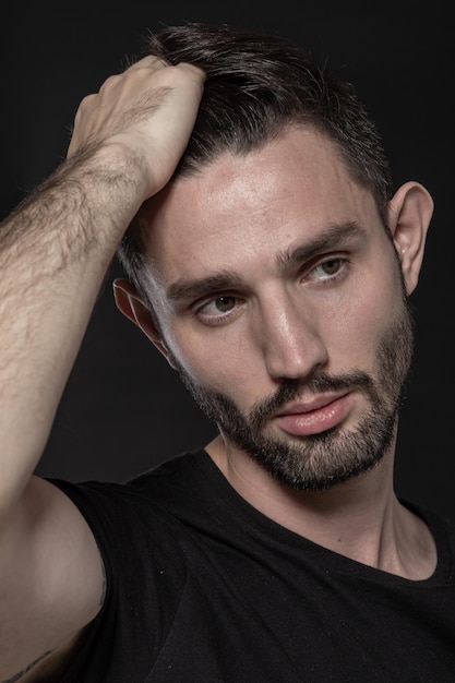 Close up portrait of a bearded guy touching his hair