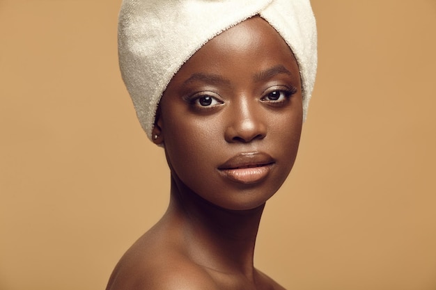 Close up portrait of beautiful African American woman having healthy and clean skin tone on a beige