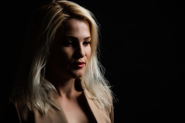 Close-up portrait of beautiful model with long blond hair on black background