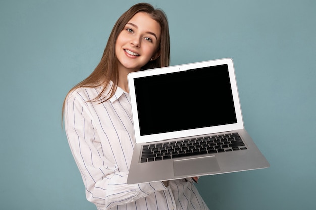 Close-up portrait of Beautiful smiling young woman holding netbook computer looking at camera