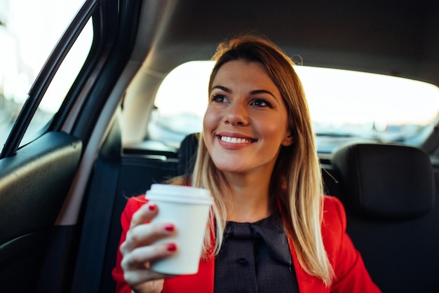 Close up portrait of a beautiful young woman holding a cup of coffee in the car