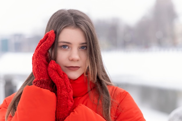 Close up portrait of blueeyed eyes girl in red warm jacket and mittens in winter outside Youth warm clothing