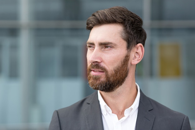 Close-up portrait of a businessman with a beautiful beard, a man in a business suit looking back