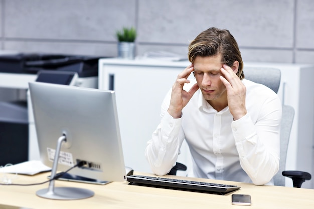 Close up portrait of businessman with headache at workplace