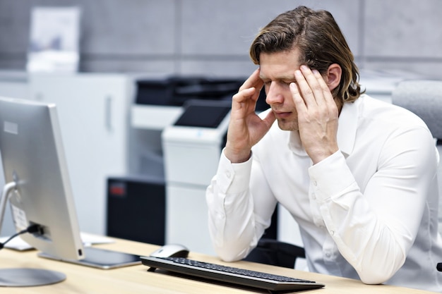 Close up portrait of businessman with headachea at workplace