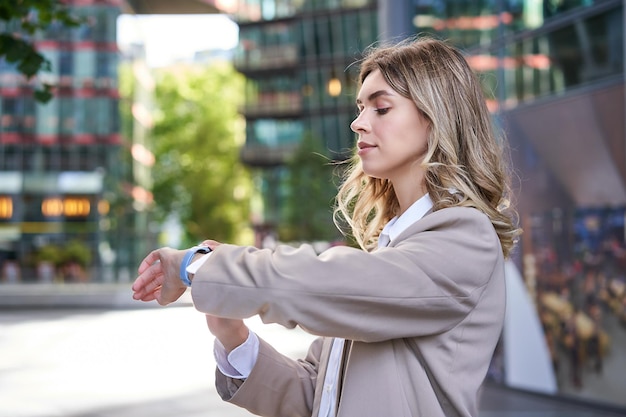 Close up portrait of businesswoman looking at her digital watch while waiting for someone outside co