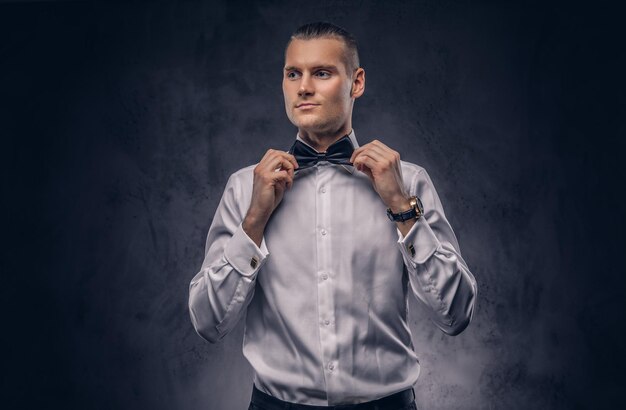 Close-up, a portrait of a casual handsome man in a white shirt against a dark background.