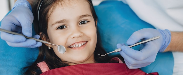 Close up portrait of a caucasian girl having an examination at the pediatric dentist while smiling at front