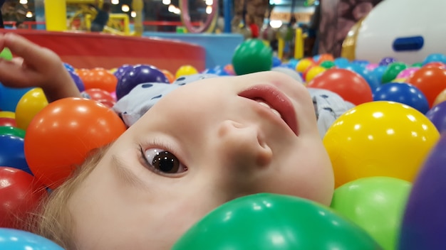 Close up portrait child playing with colorful balls in playground ball pool Activity toys for kid