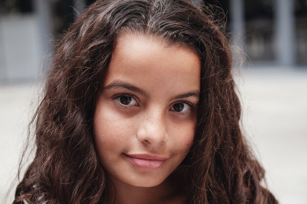 Close up portrait of a confident, charming and gorgeous mixed multicultural preteen girl with beautiful curly hair.