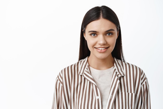 Close up portrait of confident and determined young woman smiling and looking at camera assertive standing against white background Copy space