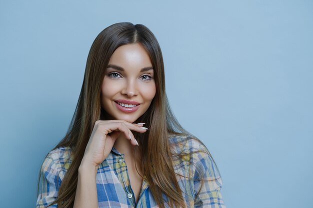 Close up portrait of cute friendly looking lady touches chin, has healthy skin