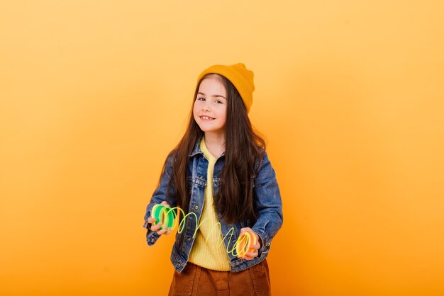 Close-up portrait of a cute little girl. Studio shot over yellow background. Childhood concept.