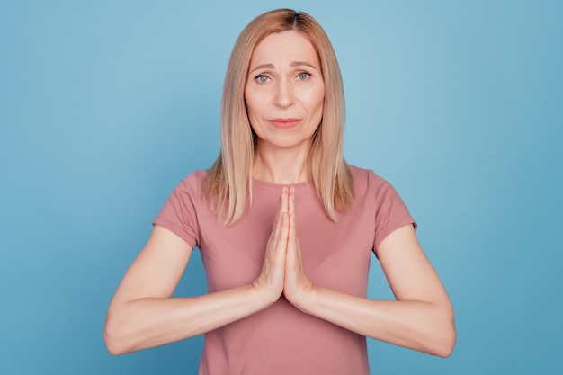 Photo close up portrait of cute young woman begging say please and show pleading gesture standing over blue background