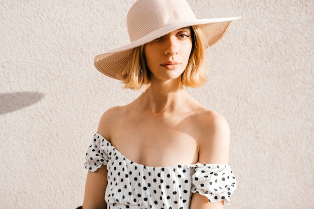 Close up portrait of elegant stylish blonde short hair girl in hat  posing over white background