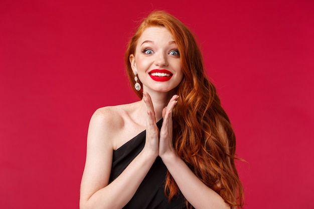 Close-up portrait of excited and eager young gorgeous redhead woman clap hands anticipating performance, smiling hopeful, awaiting for artist come on stage cant wait to hear him, red wall