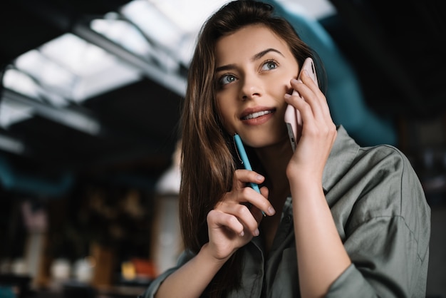 Close up portrait go young beautiful woman talking on mobile phone, thinking, sitting in cafe