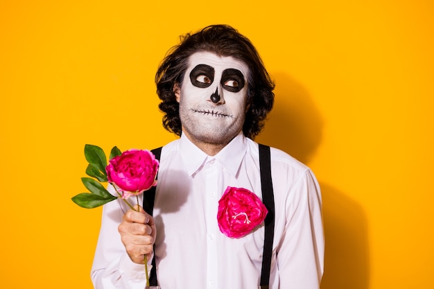 Close-up portrait of handsome creepy baleful shy cheery guy holding in hand single natural fresh rose blooming blossom first date amour isolated bright vivid shine vibrant yellow color background