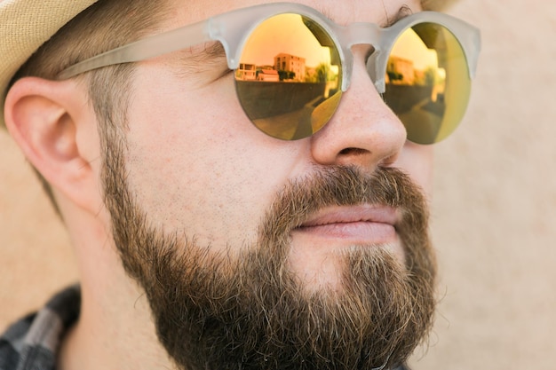 Close up portrait handsome man wearing sunglasses near wall travel vacations and summer holiday concept