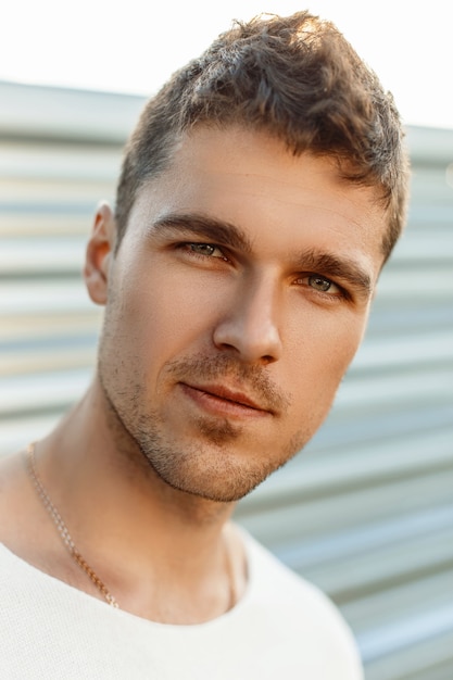 Close-up portrait of a handsome young guy with a beard in a summer day.