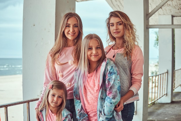 Close-up portrait of a happy family dressed in stylish clothes posing near a guardrail against sea coast.