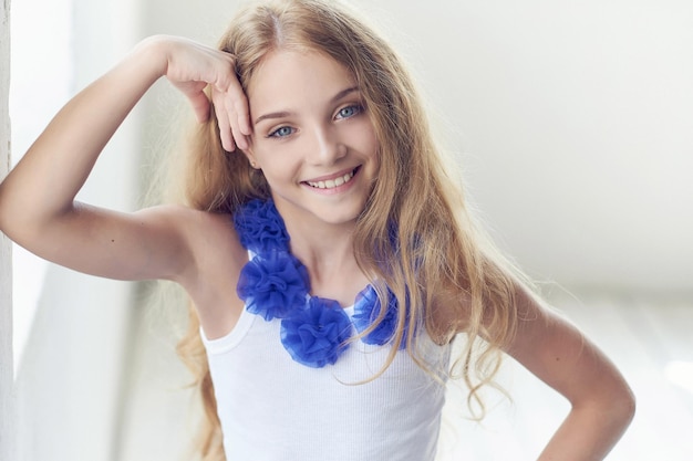 Photo close-up portrait of a happy little girl model with charming smile posing in a studio.