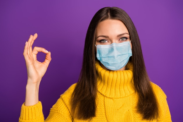 Close-up portrait of her she attractive brown-haired girl wearing gauze mask stop contamination disease cov mers influenza syndrome showing ok-sign healthy life isolated on violet color background