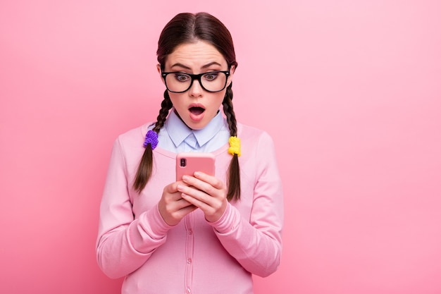 Close-up portrait of her she attractive pretty cute amazed stunned girl geek blogger using digital gadget 5g app browsing post comment feedback isolated over pink pastel color background