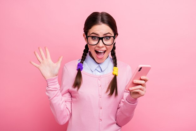 Close-up portrait of her she attractive pretty lucky ecstatic crazy overjoyed cheerful glad brown-haired girl geek using cell app follow subscribe repost share isolated pink pastel color background