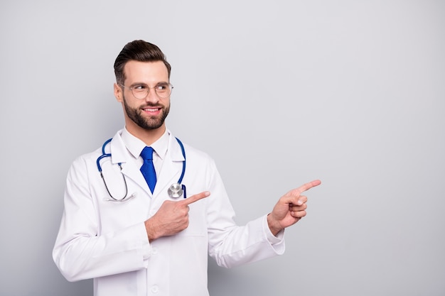 Close-up portrait of his he nice attractive smart clever cheerful bearded guy doc showing copy space ad advert new novelty solution product isolated on light white gray pastel color