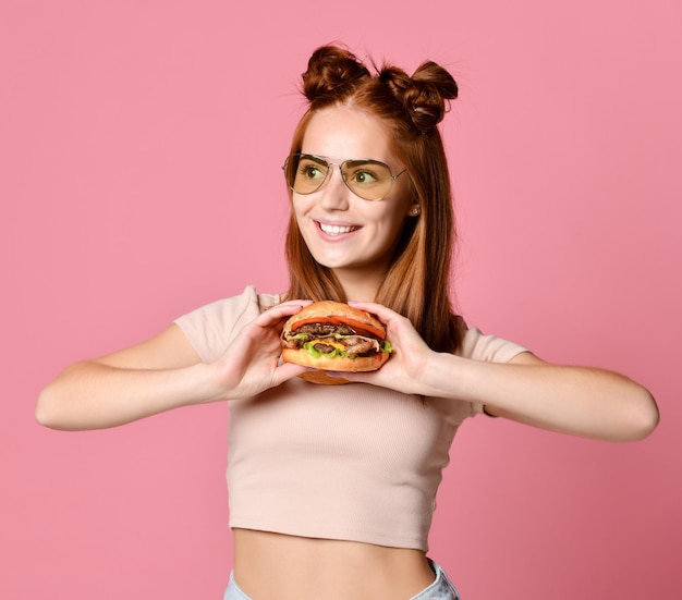 Close up portrait of a hungry young woman eating burger isolated over white background