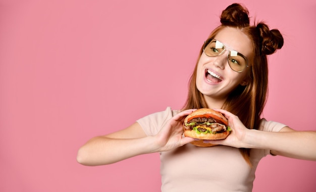 Close up portrait of a hungry young woman eating burger isolated over white background