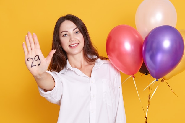 Close up portrait of joyful young woman with party balloons in hand