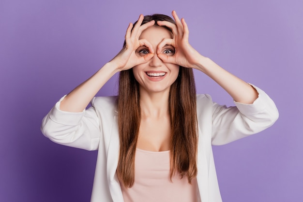 Close up portrait of lady having fun hold fingers around eyes wear formal suit posing on violet wall