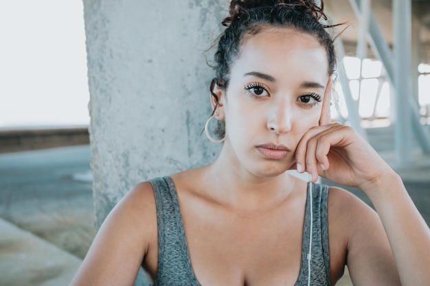 Close up Portrait looking serious young african woman taking a break after workout exercises. athlete female in sportswear relax hearing music on his phone. Urban sport .Leggings clothing and top.