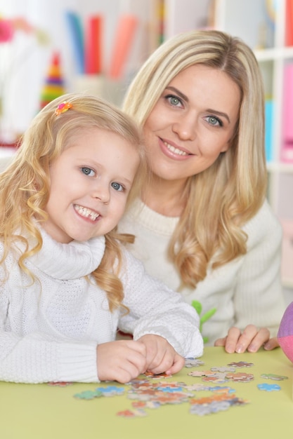 Close up portrait of mother with little daughter collecting puzzle