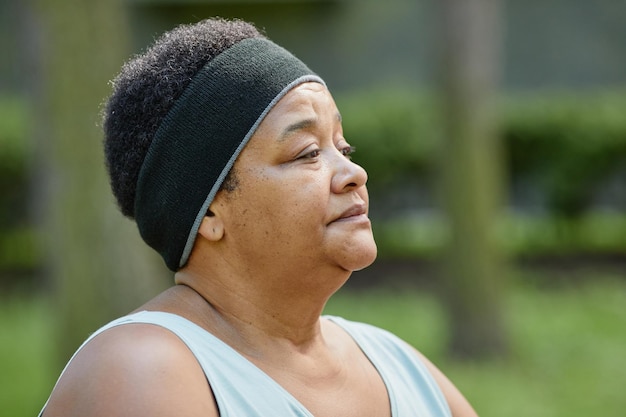 Close up portrait of overweight black woman working out outdoors and looking away copy space