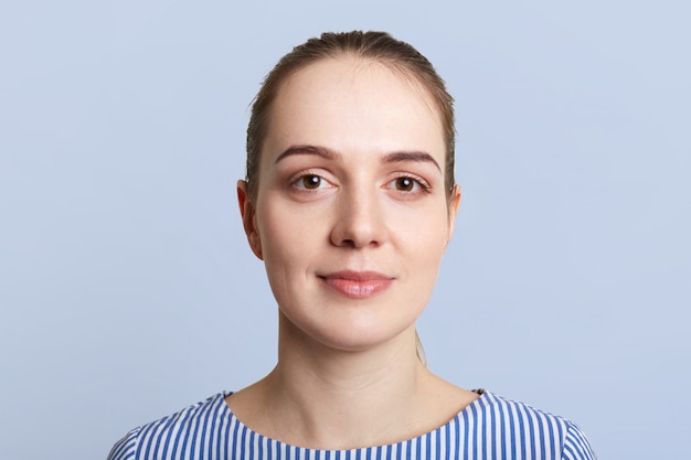 Close up portrait of pleased beautiful woman has pure skin