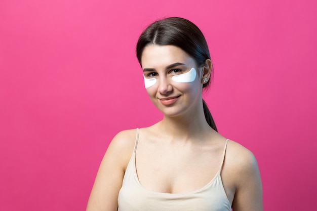 Close up portrait of pretty attractive girl with naked shoulders using patches under eyes