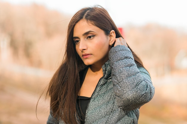 Close up portrait of pretty indian young woman enjoying warm autumn sunny day vacation outdoors copy