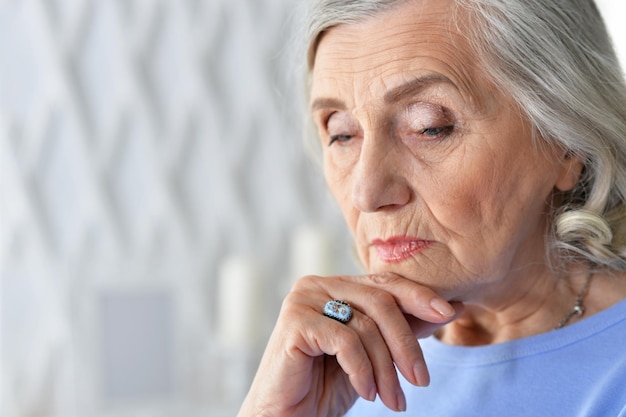 Close up portrait of sad ill senior woman posing at home