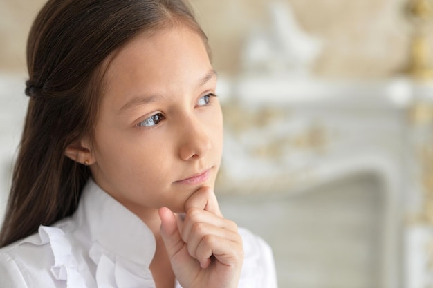 Close up portrait of sad little girl in white blouse