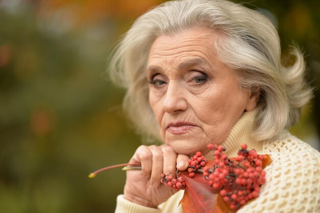 Close up portrait of sad senior woman in autumn park