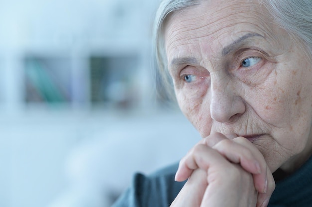 Close up portrait of sad senior woman sitting at table