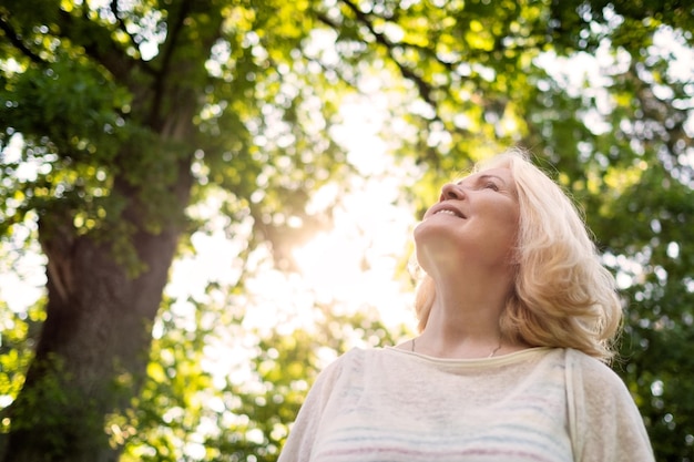 Close up portrait of senior woman by the tree