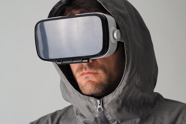 Close up portrait of serious man in hoodie and VR glasses.