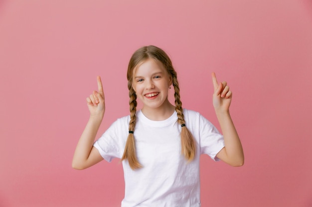 Close up portrait she is a cute attractive joyful cheerful girl pointing her index finger up to find a solutionisolated pink pastel color background