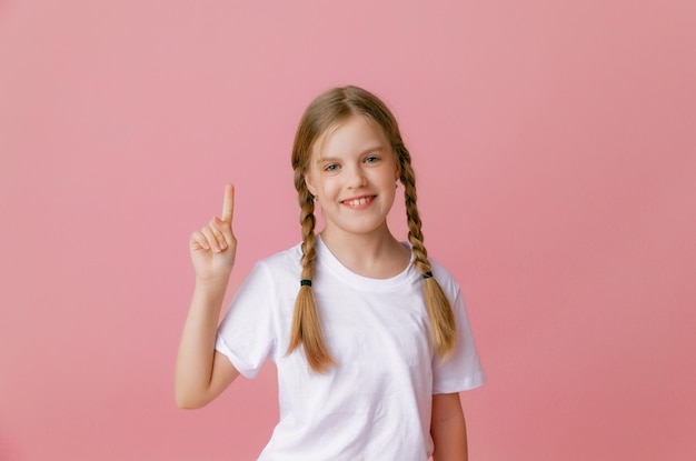 Close up portrait she is a cute attractive joyful cheerful girl pointing her index finger up to find a solutionisolated pink pastel color background